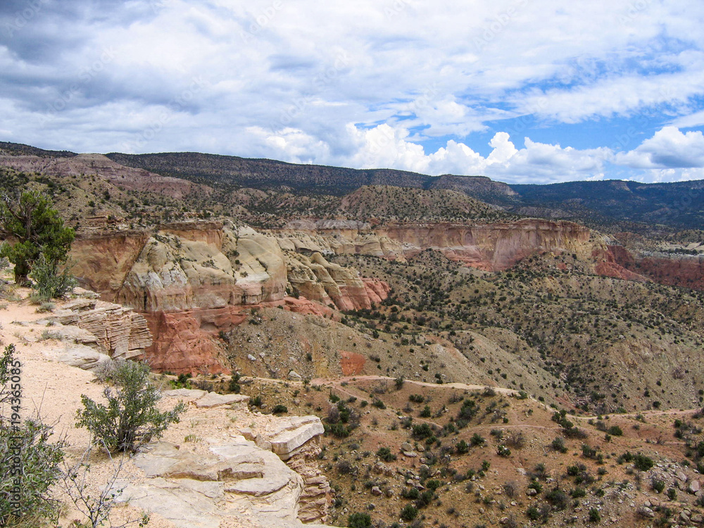 Cliffs, canyons and desert landscape at Ghost Ranch, New Mexico seen from Chimney Rock trail under a cloudy western sky Cliffs, canyons and desert landscape at Ghost Ranch, New Mexico seen from Chimney Rock trail under a cloudy western sky