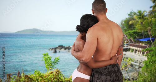 Black couple on honeymoon in Caribbean looking out over the ocean. Man and woman on vacation at island resort in love photo