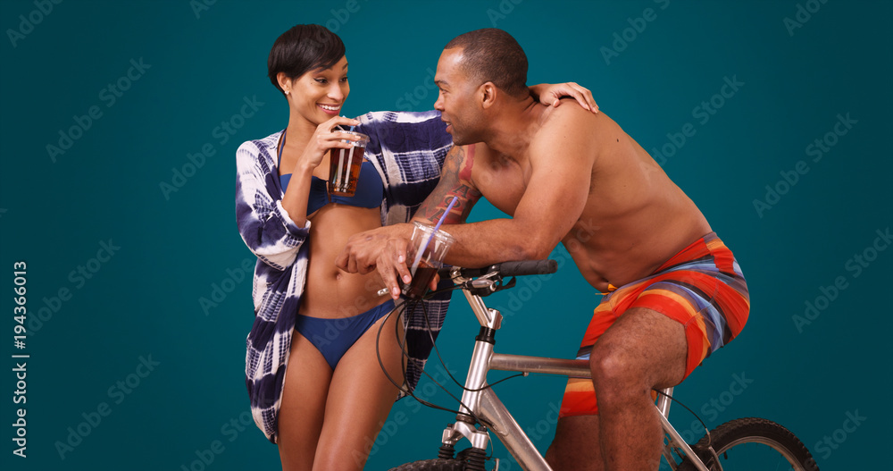 African American couple flirt on a blue background. Two black adults talks while on a bicycle on a blank backdrop