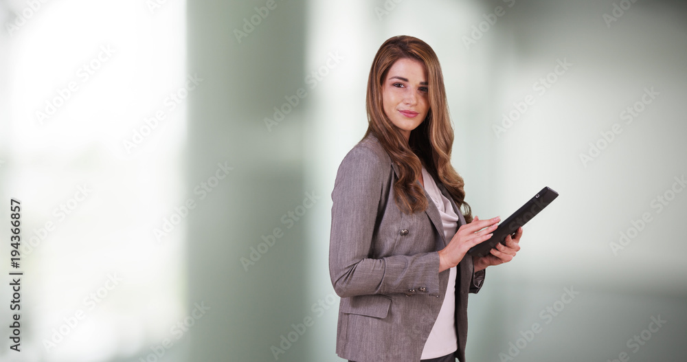 Attractive business woman intern using tablet in the office. Cute Woman in 20s using pad in the hallway