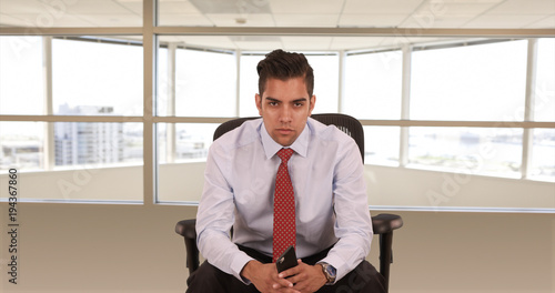 Quadro em tela Portrait of young Hispanic business professional sitting in office chair looking at camera