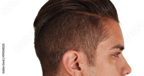 Close up Side view of Hispanic man with cool undercut standing with white background. Profile close up portrait of Latino millennial