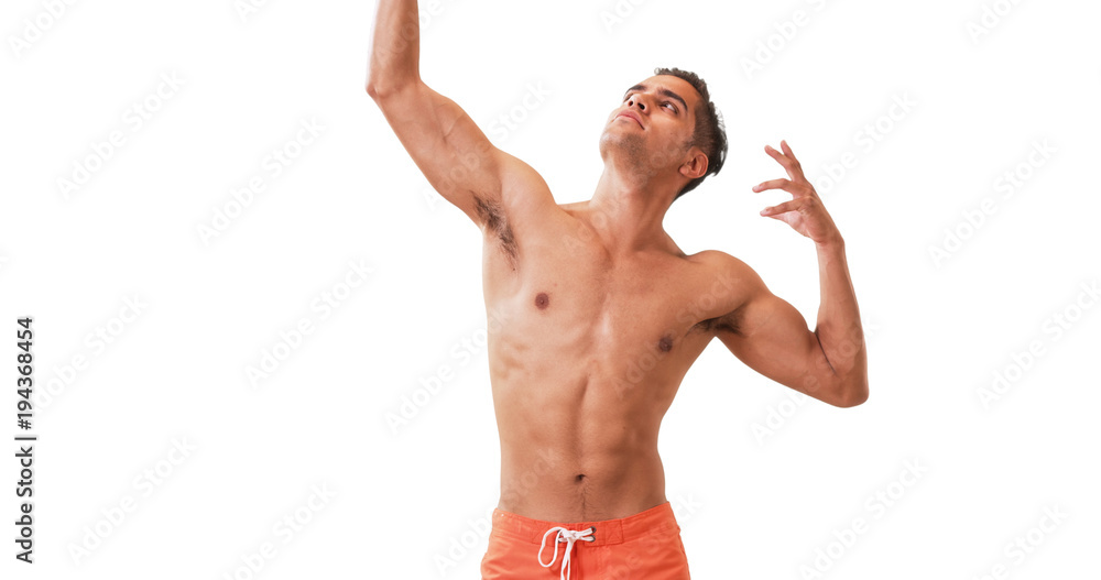 Happy Millennial Hispanic man posing in swim trunks on white background. Young guy doing silly poses having fun laughing.