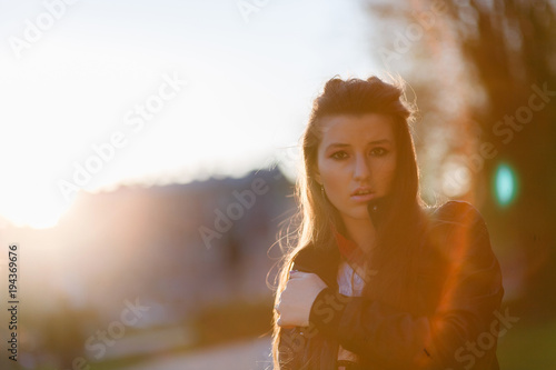 Rocker,punk woman.Young rock woman in black leather jacket casual standing with city background at sunset. Rock bad girl.Sexy attractive woman with punk rock fashion styling. Noise added