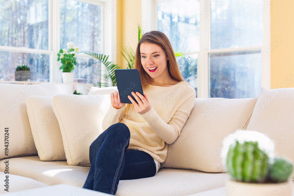 Young woman reading with an e-reader in a large interior room Young woman reading with an e-reader in a large interior room