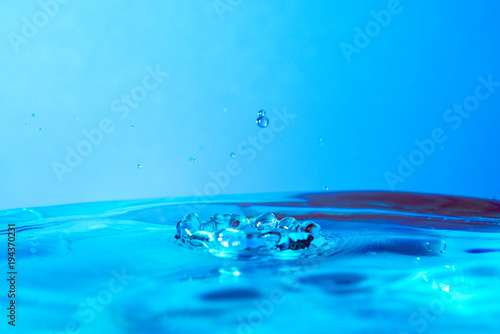 drop of water falling in blue water and blue background.