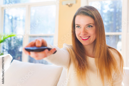 Young woman watching with remote control watching TV in the living room