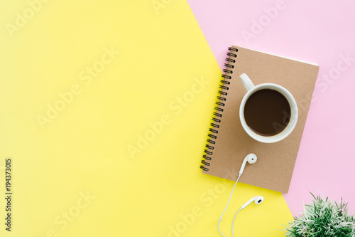 Creative flat lay photo of workspace desk. Top view office desk with notebooks, plant, coffee cup, earphone and copy space on pastel color background. Top view with copy space, flat lay photography.