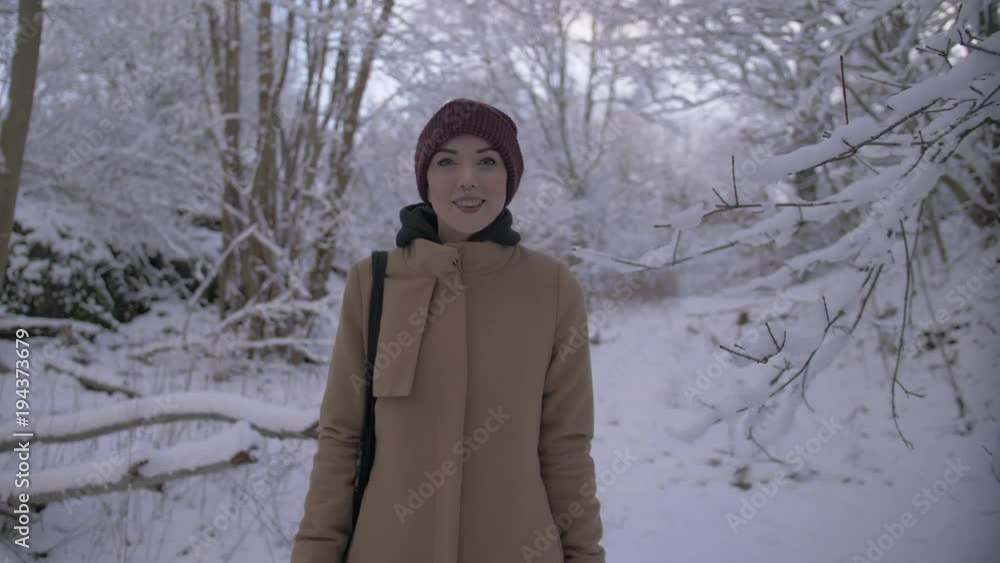Young woman walks through winter forest and smiles Young woman walks through winter forest and smiles