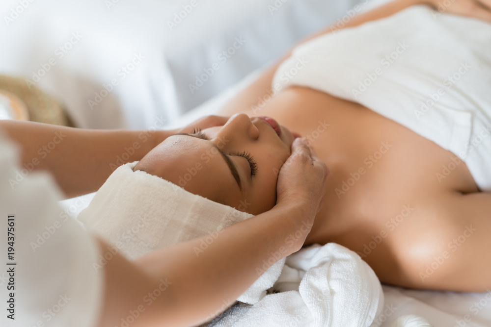Beautiful Asian girl relaxing receiving facial massage in a spa salon Beautiful Asian girl relaxing receiving facial massage in a spa salon