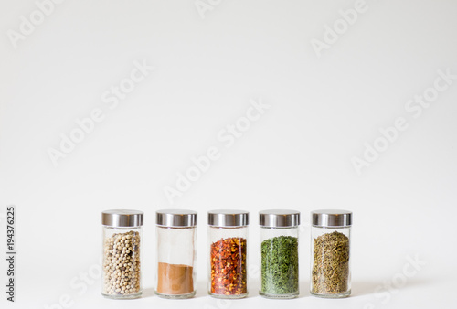 Fototapeta Naklejka Na Ścianę i Meble -  Row of five spice jars isolated on white background