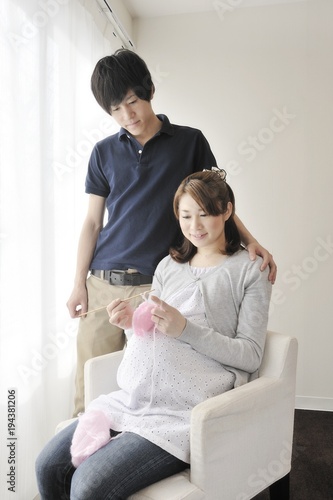 編み物をする妊婦と見守る夫