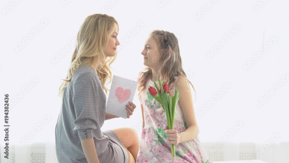 Daughter gave her mother a bouquet of tulips and a postcard made by own hands. Daughter gave her mother a bouquet of tulips and a postcard made by own hands.