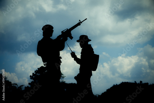 Silhouette image of two armed soldiers with blue sky background