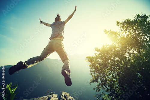 Slika na platnu hipster woman hiker jumping on cliff's edge