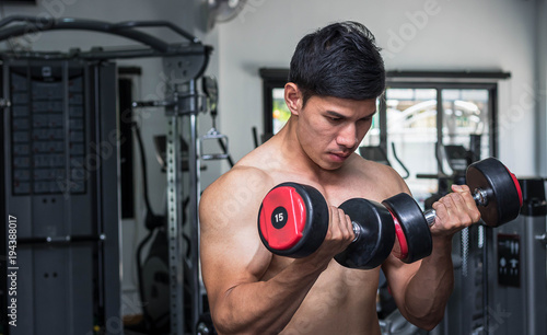 Men exercise in gym with dumbbell