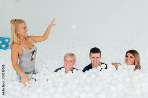 Happy Friendly family surrounded by white plastic balls in the dry pool. photo