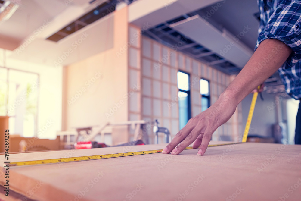 The carpenter is using a tool to measure the size of the wood for use in his work. The carpenter is using a tool to measure the size of the wood for use in his work.
