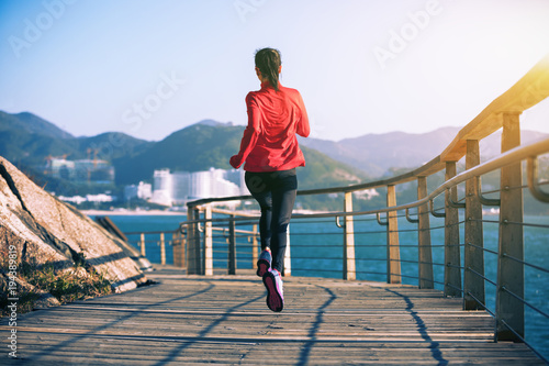 sporty fitness female runner running on seaside boardwalk © lzf