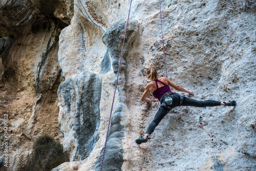 Girl climbs rock tufa top rope, back view, Turkey