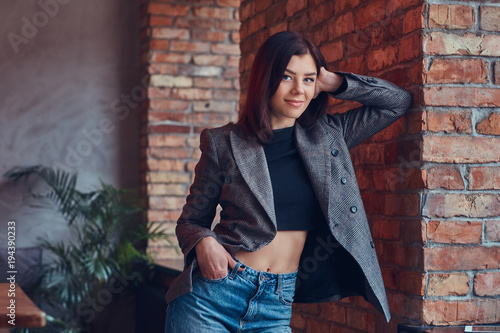 Portrait of a sexy slim young female in a jacket and jeans leani