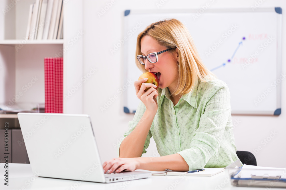 Businesswoman is eating apple in her office. Businesswoman is eating apple in her office.