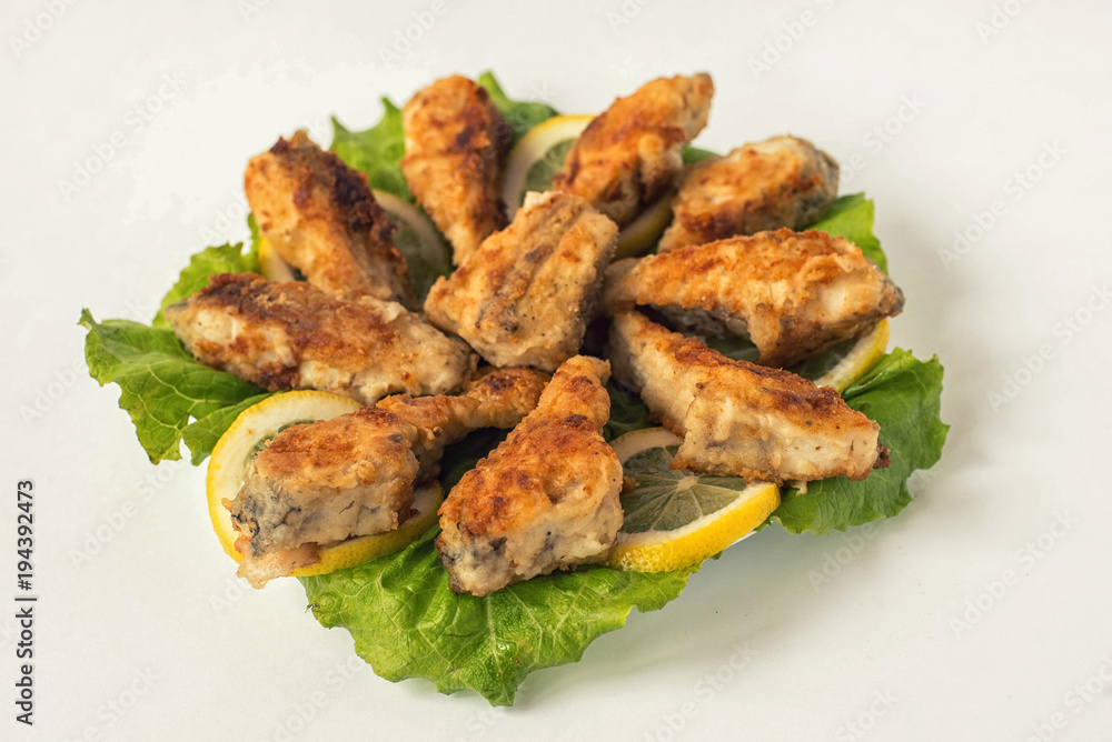 fried fish on a white plate with lettuce and lemon fried fish on a white plate with lettuce and lemon