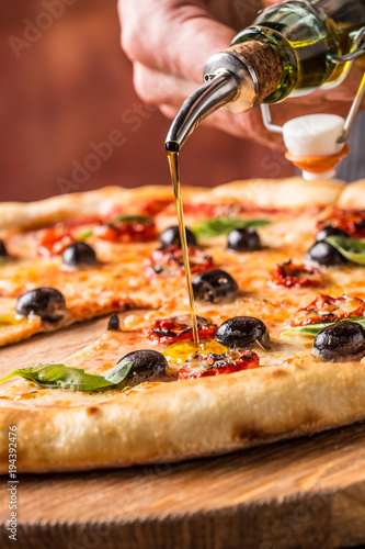 Chef and pizza. Chef pouring olive oil on  pizza in hotel or restaurant