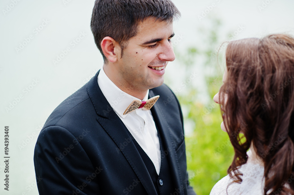 Wedding couple at breathtaking landscape with rock and lake.