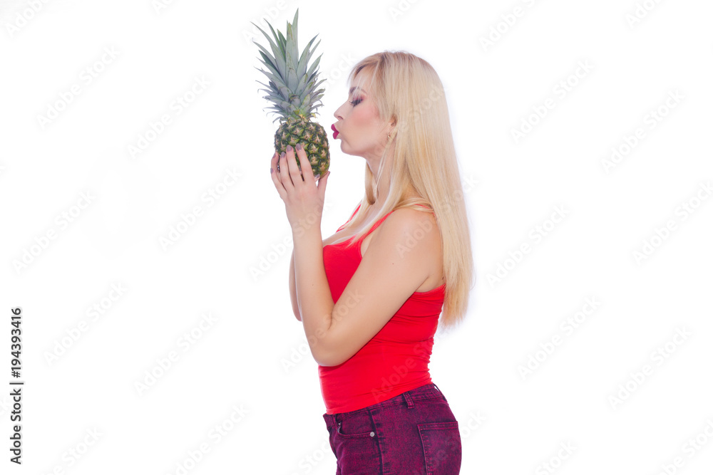 Portrait of a profile of a blonde in a summer outfit. He holds a pineapple and kisses his lips. Copy space Portrait of a profile of a blonde in a summer outfit. He holds a pineapple and kisses his lips. Copy space