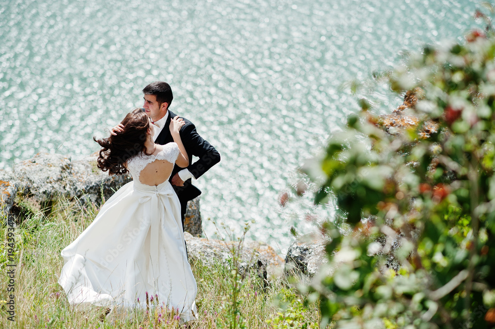 Wedding couple at breathtaking landscape with rock and lake. Wedding couple at breathtaking landscape with rock and lake.