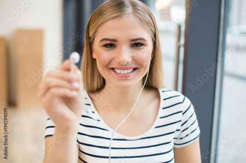 Happy positive woman showing you her headphone