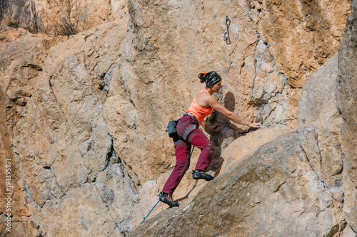 Woman climbs a yellow rock with a rope, lead, side view