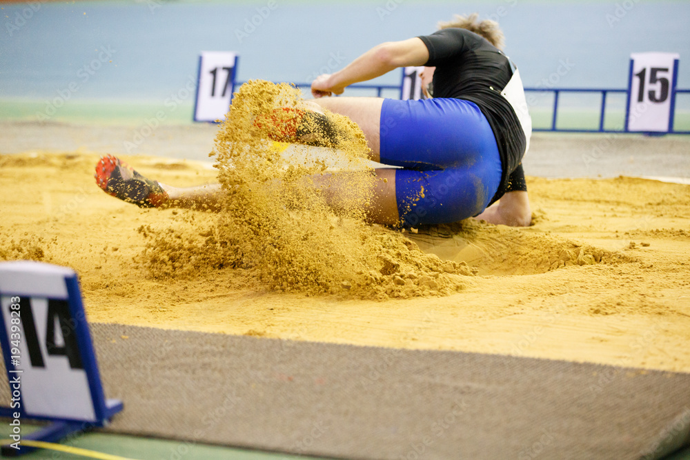 Sportsman landing into sandpit in long jump competition. Track and