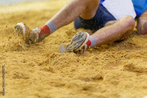 Foto Sportsman landing into sandpit in long jump competition