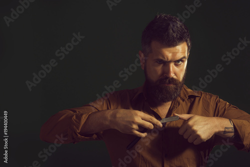 Fotografía Brutal caucasian hairdresser demonstrating sharp blade of barbershop accessory