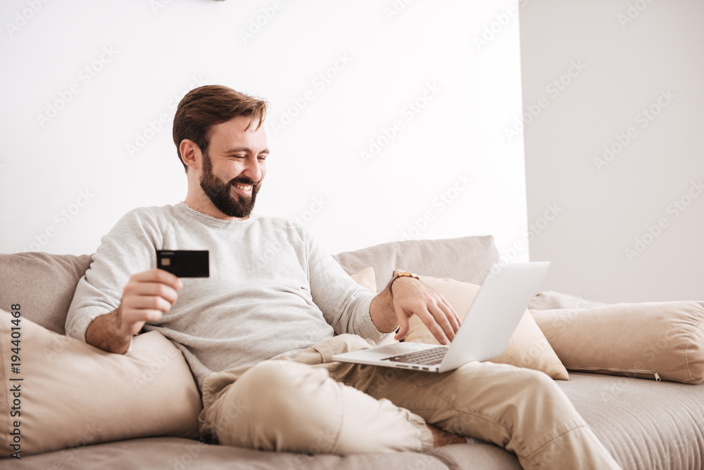 Portrait of a satisfied man shopping online with credit card