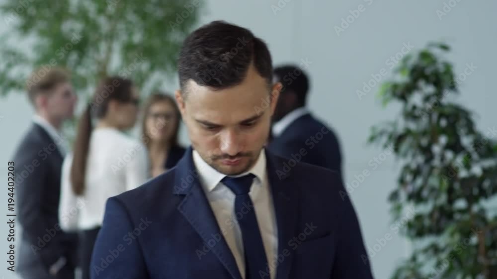 PAN of successful businessman in suit and necktie looking at notebook, then smiling for camera PAN of successful businessman in suit and necktie looking at notebook, then smiling for camera