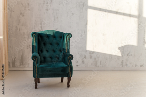 Green armchair on white wall background near window. Loft style