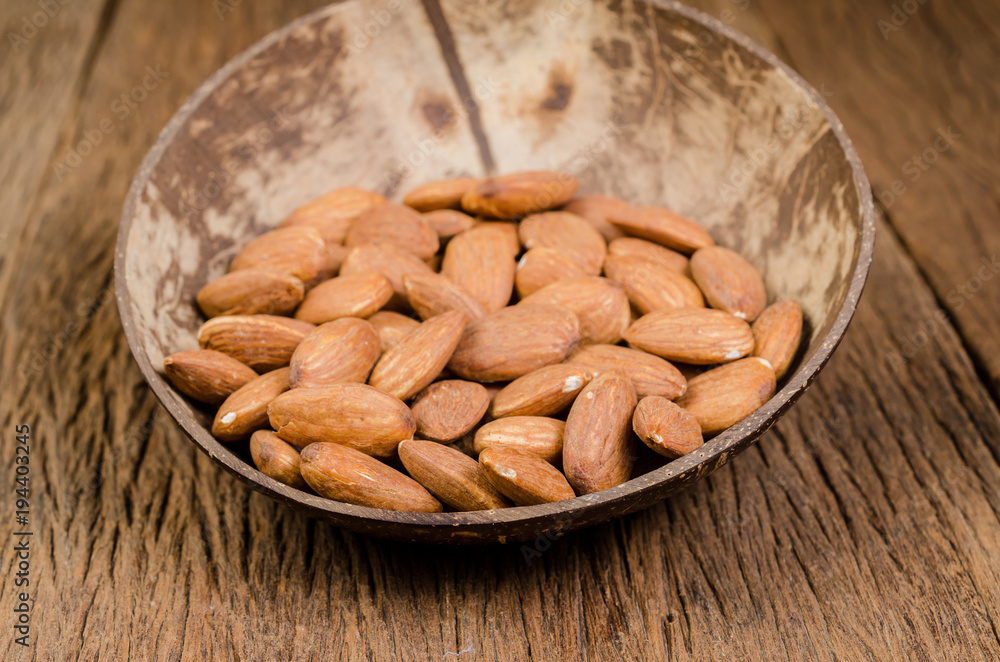 almond in wooden bowl on wooden board