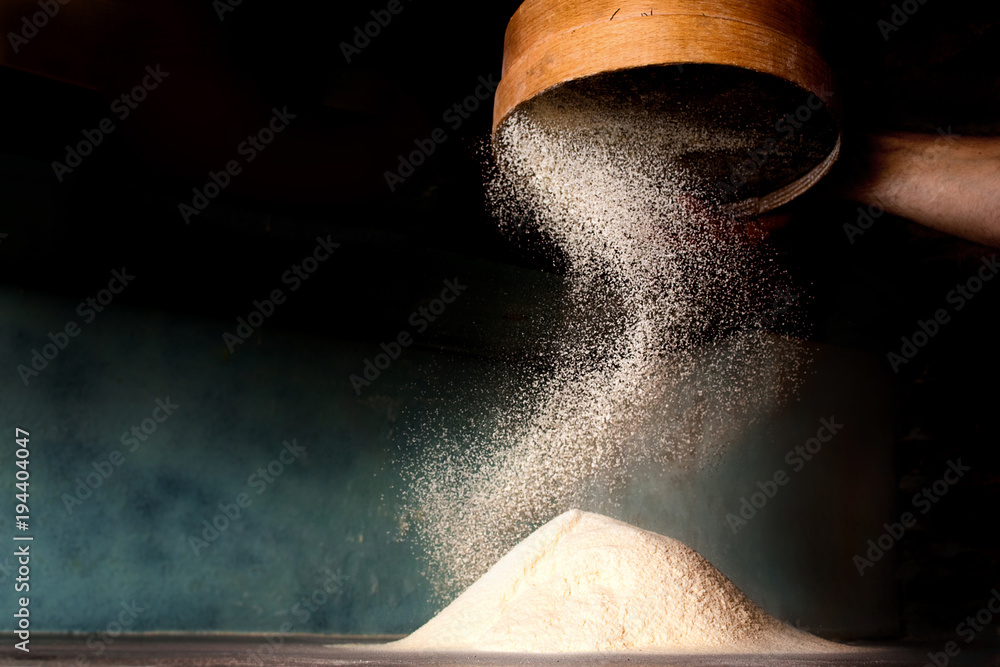 Foto Sifting flour from old sieve.