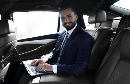 smiling businessman sitting in the back seat of a prestigious car © ASDF