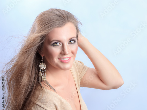 Closeup portrait of a pretty young and happy blonde woman on light background