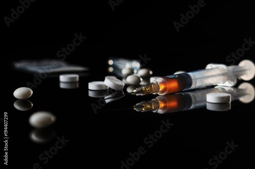 Different drugs - powder and pills and a syringe on a black background. Stop drug addiction. International Day against Drug abuse. Hard drugs on table. photo