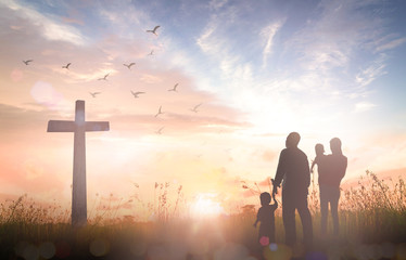 Christian family with children looking at the cross at sunrise, concept of resurrection, hope and easter sunday