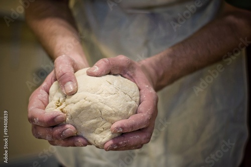 Hands rumple dough in kitchen.Defocus in the background.