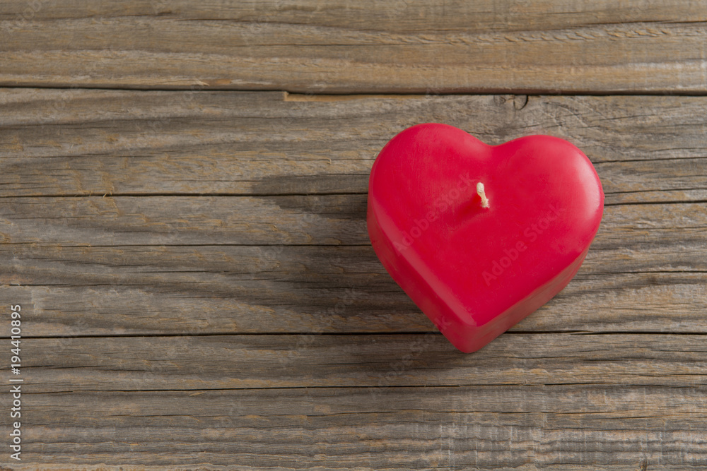 Red heart shaped candle on a wooden surface Red heart shaped candle on a wooden surface