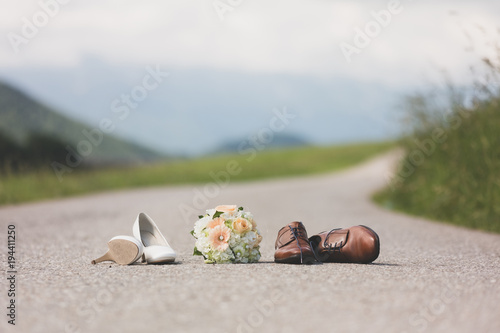 Hochzeitsschuhe und Hochzeitsblumenstrauß vom Hochzeitspaar auf der Straße bei der Hochzeit