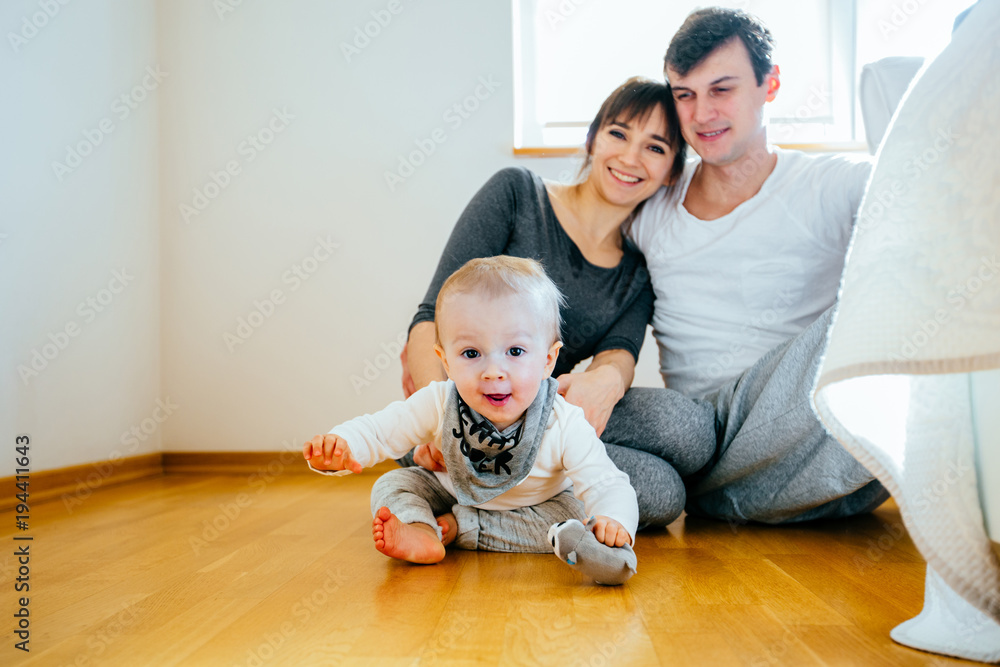 Portrait of cute baby crawling on the floor with mother and father in the background. First small achievements concept. Portrait of cute baby crawling on the floor with mother and father in the background. First small achievements concept.