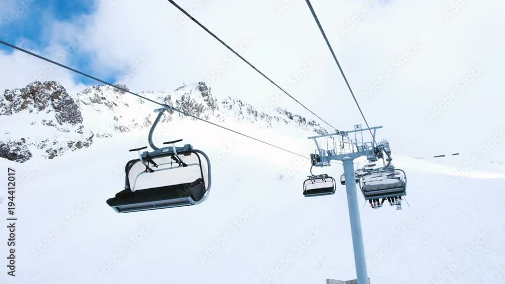 View from the chairlift in motion to the top, four-seat lifts work at the ski resort, slow motion. View from the chairlift in motion to the top, four-seat lifts work at the ski resort, slow motion.